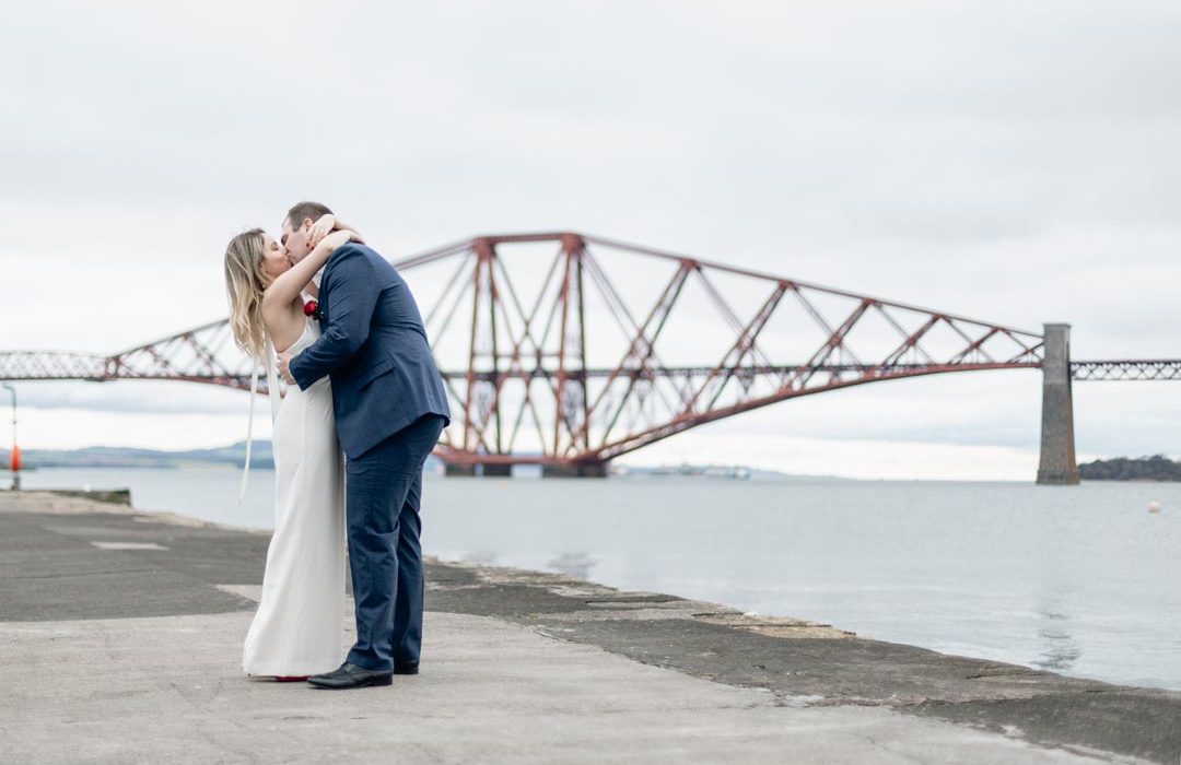 Wedding couple kissing in front of the forth rail bridge