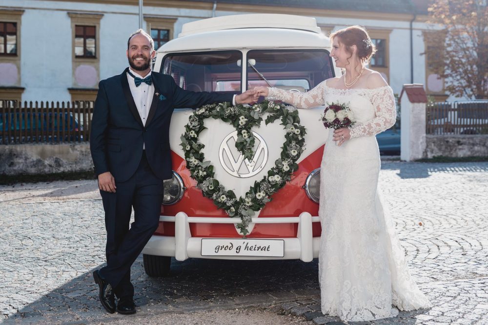 couple standing in front of their VW campervan wedding car