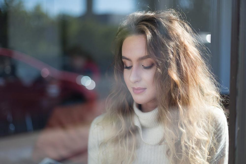 Young beautiful woman sitting inside a coffee shop on a sunny day