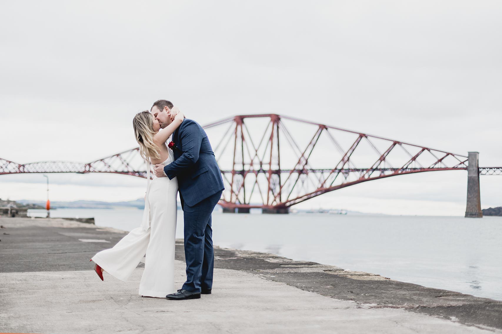 Newly wed couple stealing a kiss in front of the forth rail bridge in South Queensferry