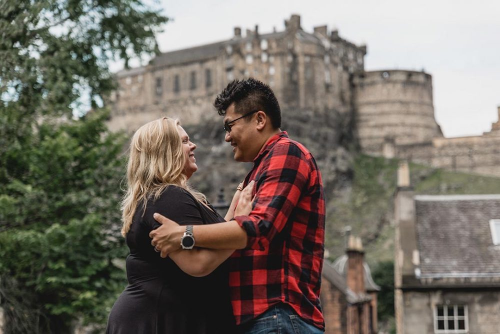 a couple hugging in front of the edinburgh castle