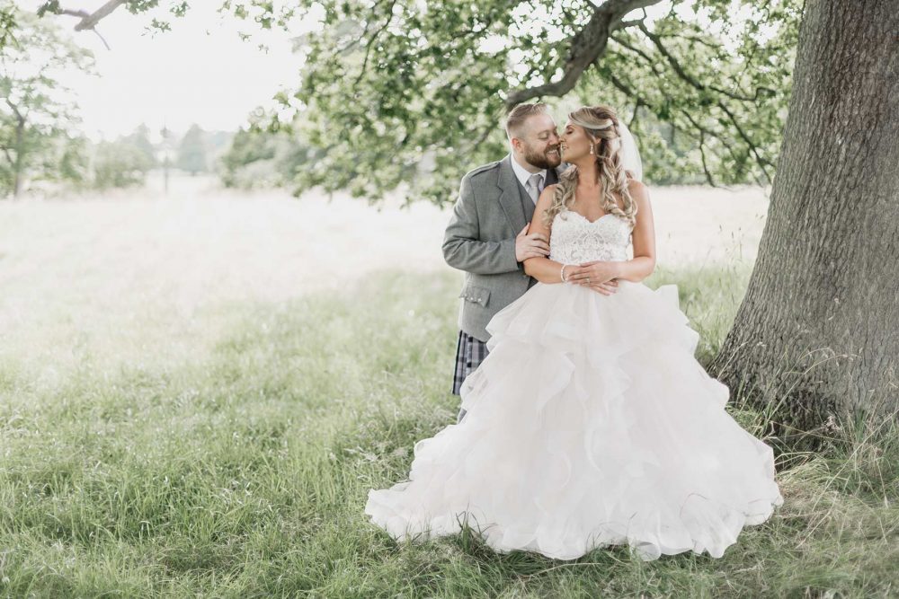 Romantic Wedding couple stealing a kiss under a tree